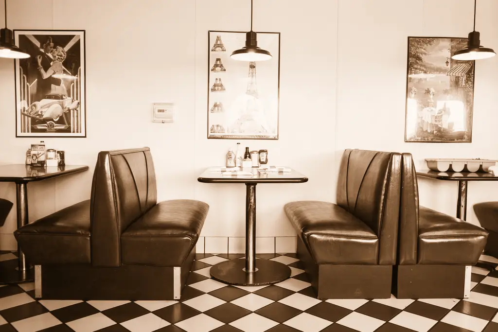 Rows of black vinyl diner booths on a checkerboard floor under pendant lamps