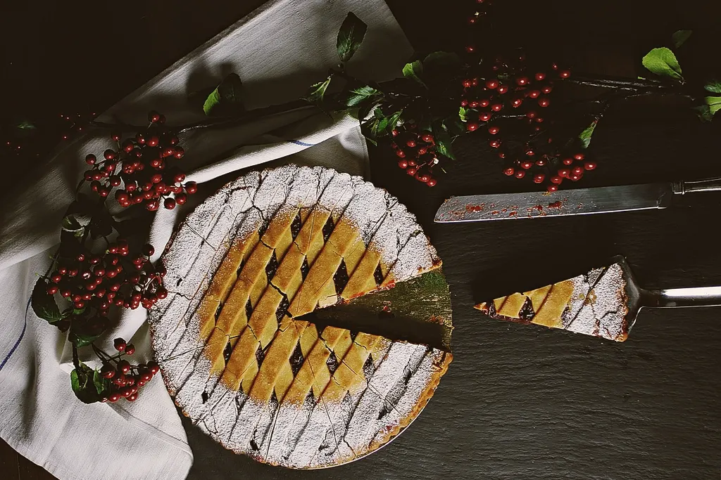 A lattice-top fruit pie dusted with sugar, one slice cut and lifted out